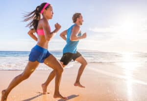 Healthy active runners couple running on beach working out cardio together. Fitness sports lifestyle.